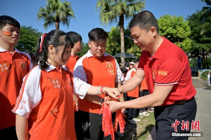 資料圖：廣西華僑實(shí)驗(yàn)高中的教師為高三學(xué)子系上紅絲帶，盼望學(xué)子高考必勝。 俞靖 攝